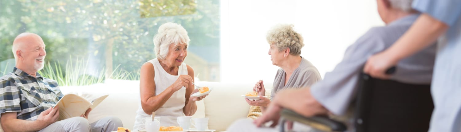 A group of seniors/older adults eating and talking at a nursing home or assisted living facility