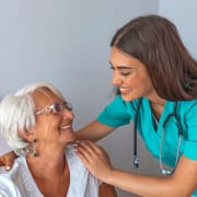 A nurse or CNA interacting with a patient in a nursing home or assisted living facility