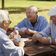 A group of older men playing cards outside (nursing home or assisted living scene)